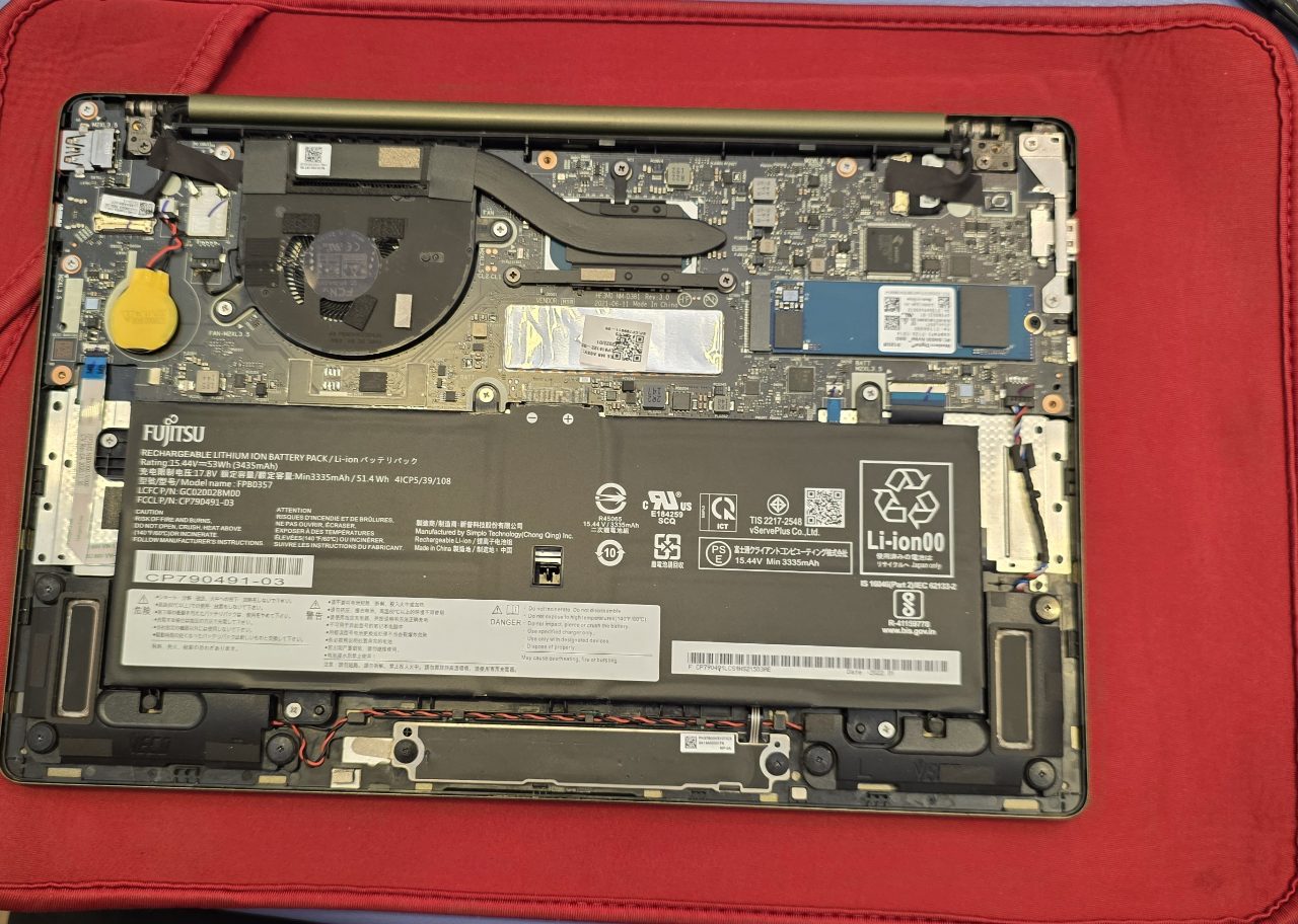 裏蓋を取り外したFujitsuノートパソコンの内部。バッテリーと青いM.2 NVMe SSDが見える