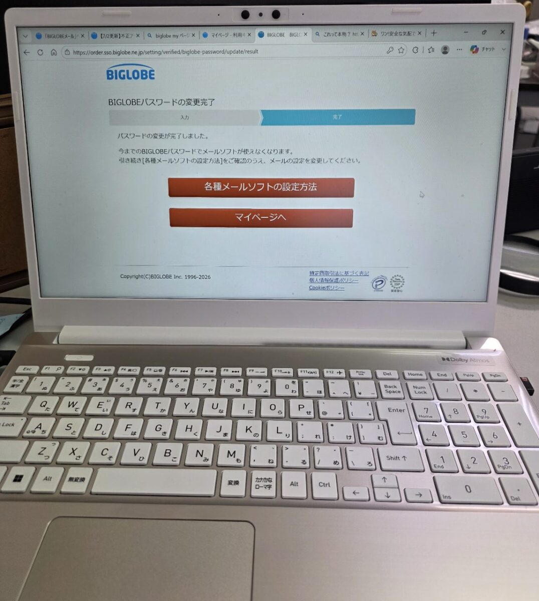 ノートPCの画面に表示されたBIGLOBEのウェブページ。「パスワードの変更完了」のメッセージとメールソフトの設定方法への案内が表示されている。