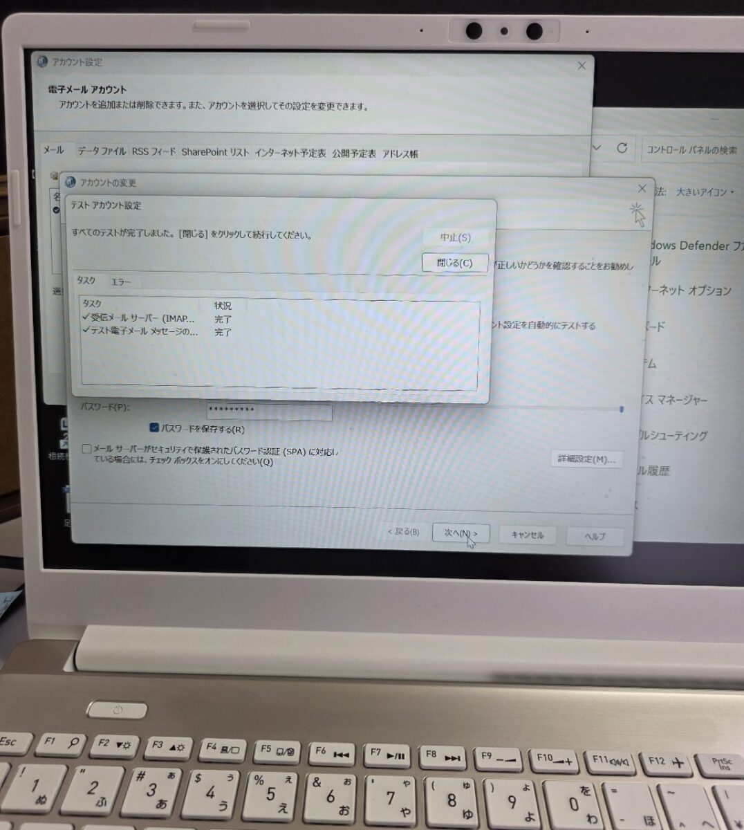 ノートPCのOutlookアカウント設定画面。メールアカウントのテストが正常に完了し、送受信が可能な状態になっていることを示す緑色のチェックマーク。