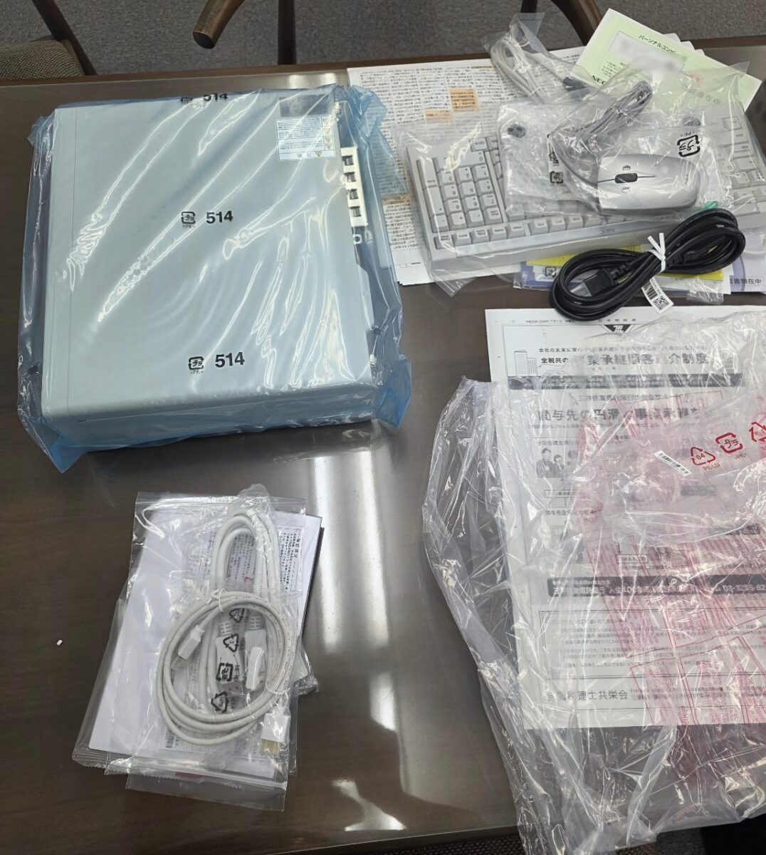 テーブルの上に広げられたNEC LAVIEパソコン本体、キーボード、マウス、ケーブル、取扱説明書などの付属品がビニール袋に入った状態。