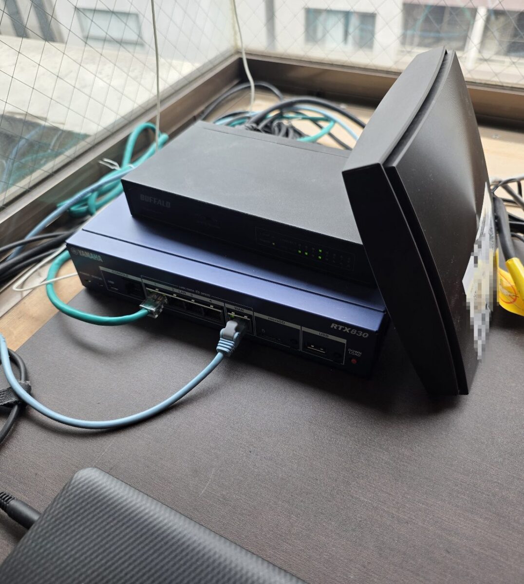 YAMAHA製ルーター（RTX830）とBUFFALO製ハブが積み重ねて設置されている様子。
