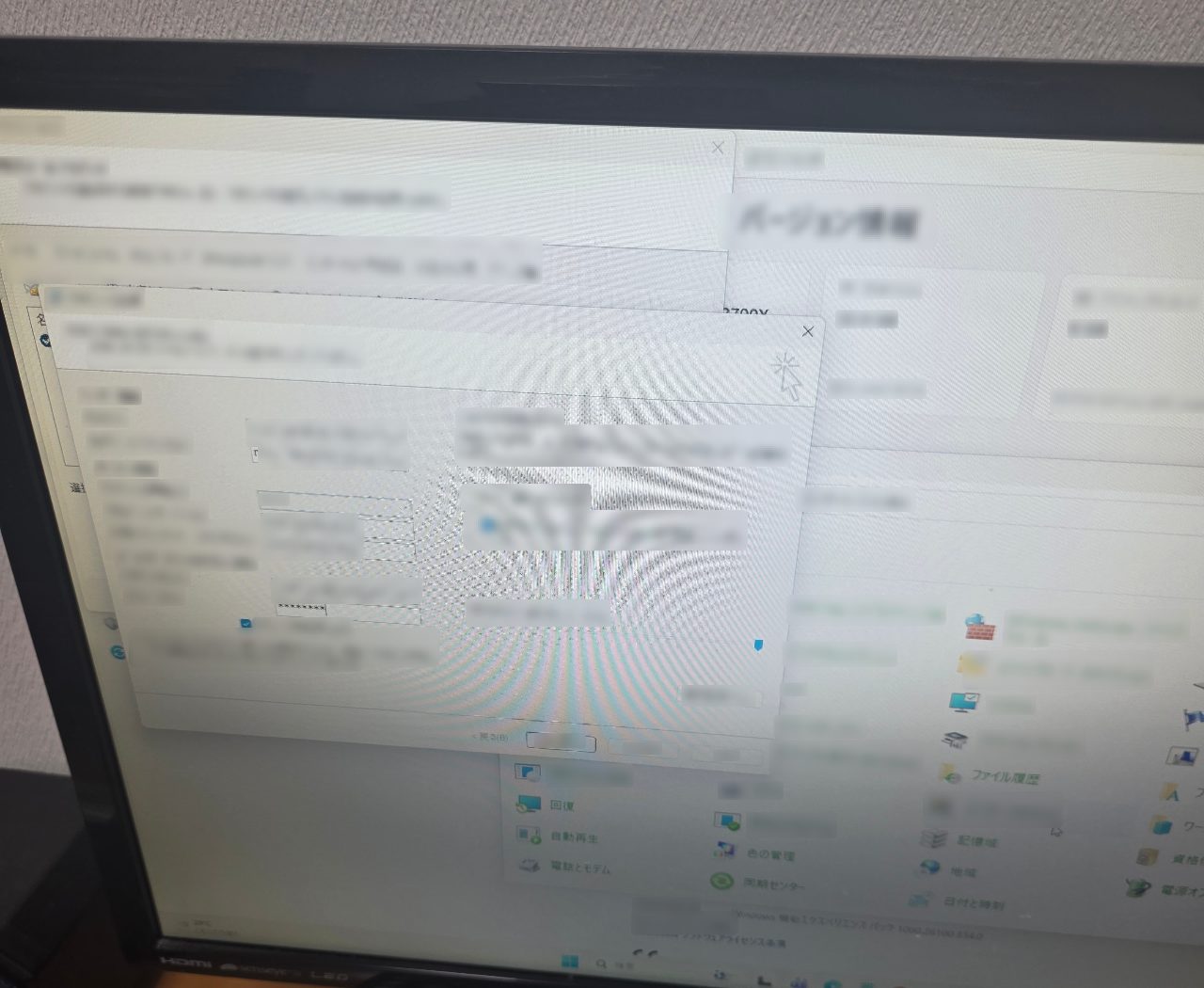 Windowsのシステム情報画面と、アカウント認証に関するポップアップが表示されたパソコンのモニター
