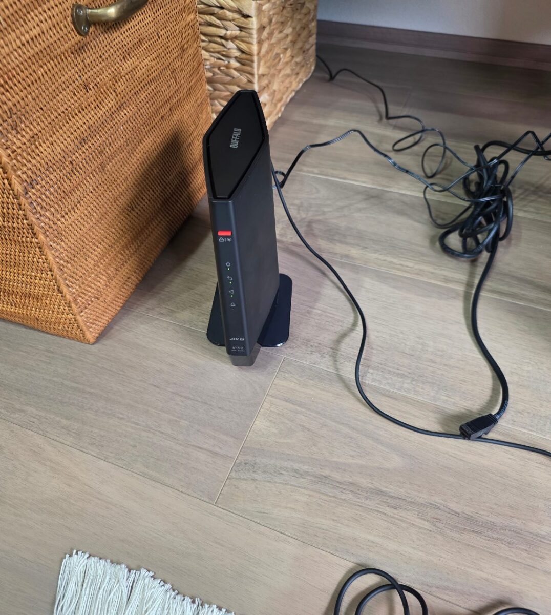 床に設置された黒いBUFFALO製ルーター、LEDが点灯している様子