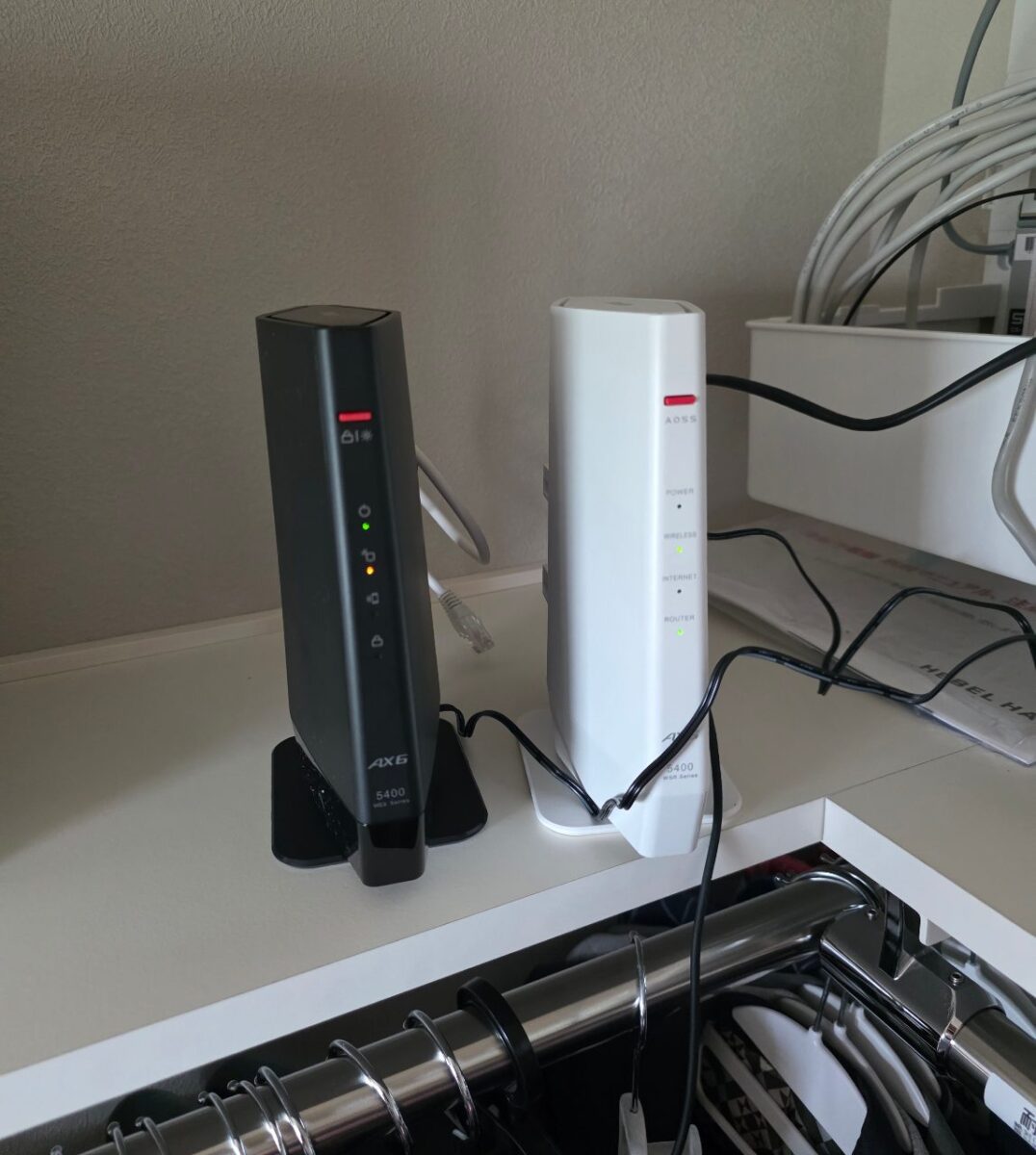 並んで設置された黒と白のBUFFALO製ルーター、両方ともLEDが点灯している様子